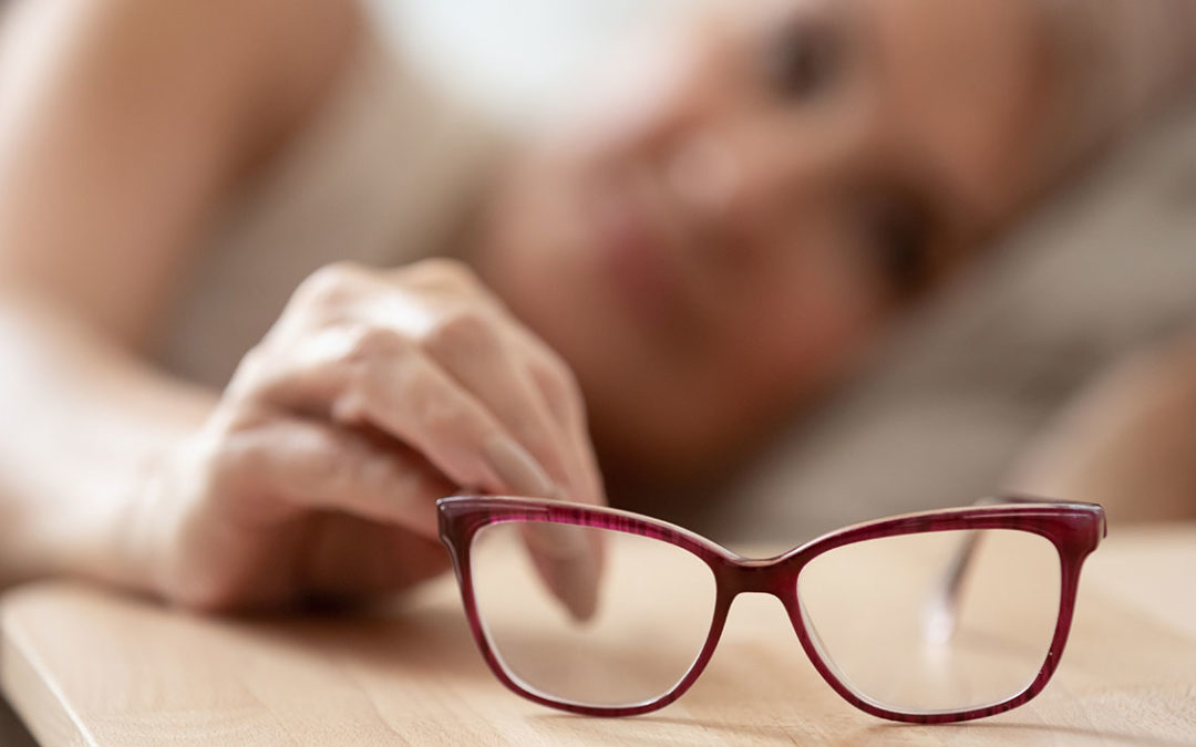 elderly lady putting eye glasses on bed side stand