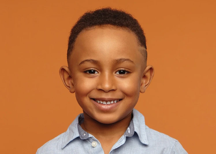 a young boy smiling against an orange background