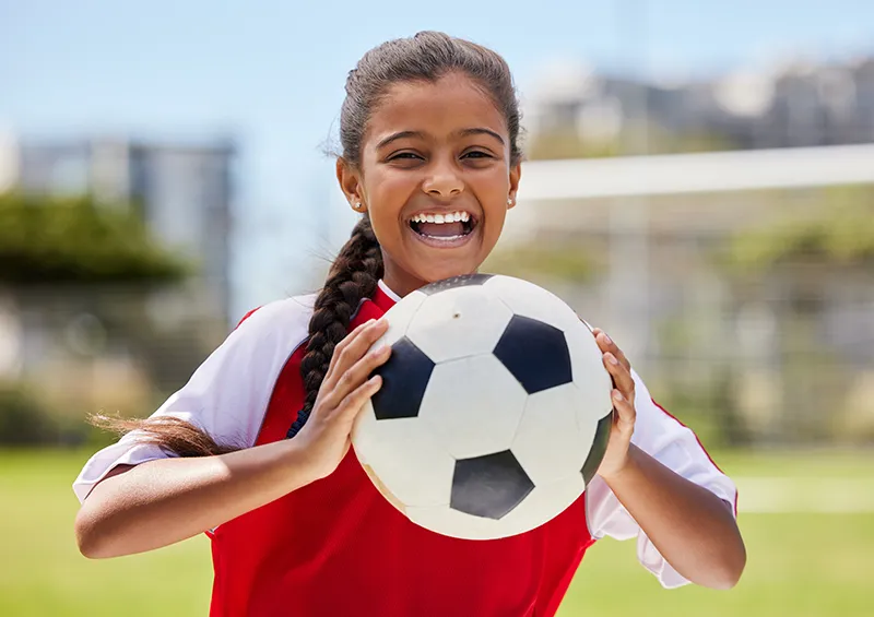 sports-eye-safety a young girl holding a soccer ball outdoors